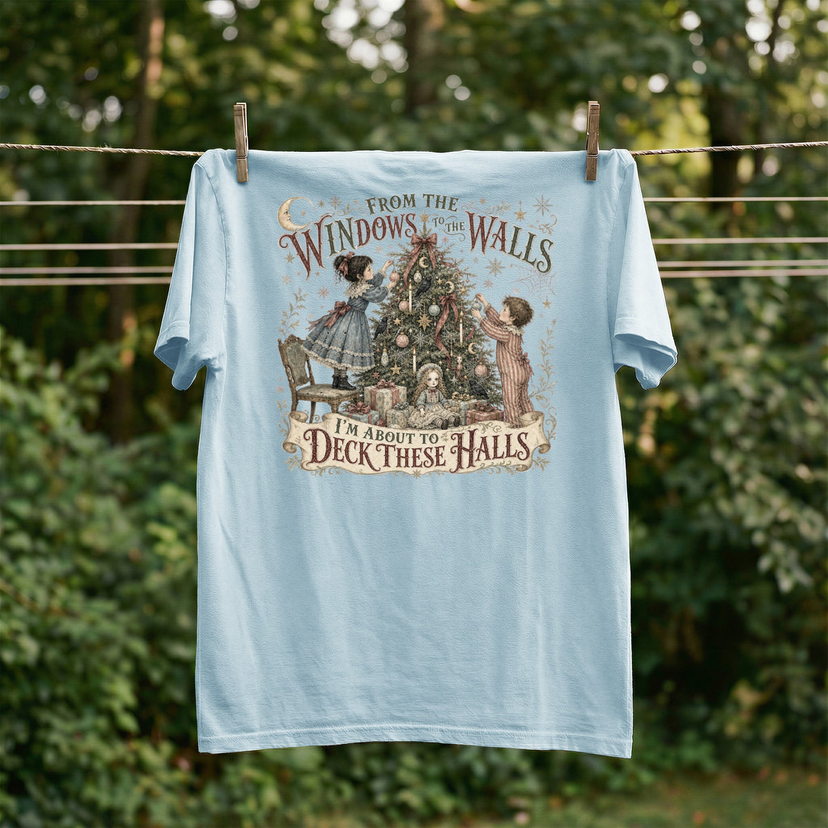 Light blue t-shirt with a vintage illustration of children decorating a Christmas tree and text.