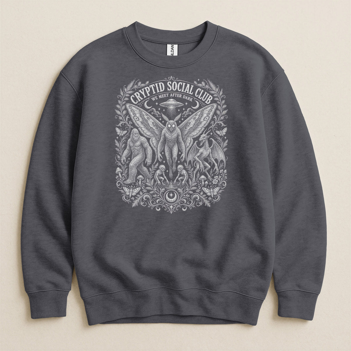 Dark grey sweatshirt with "Cryptid Social Club We Meet After Dark" text and cryptid illustrations.