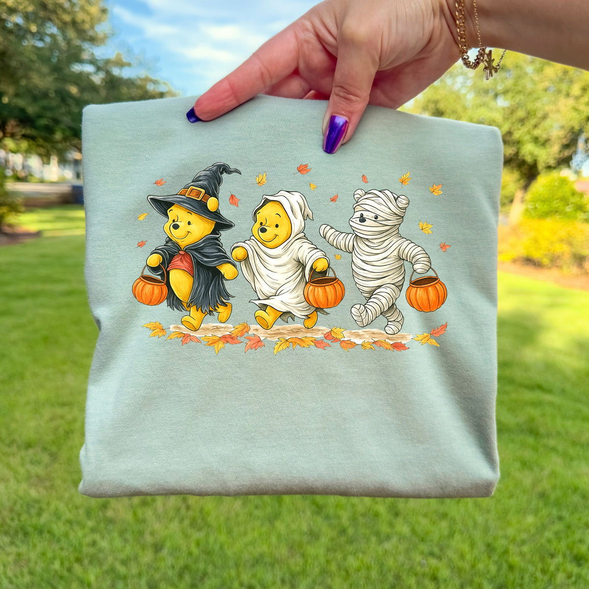 Winnie the Pooh characters dressed for Halloween, holding pumpkin buckets on a background of leaves.