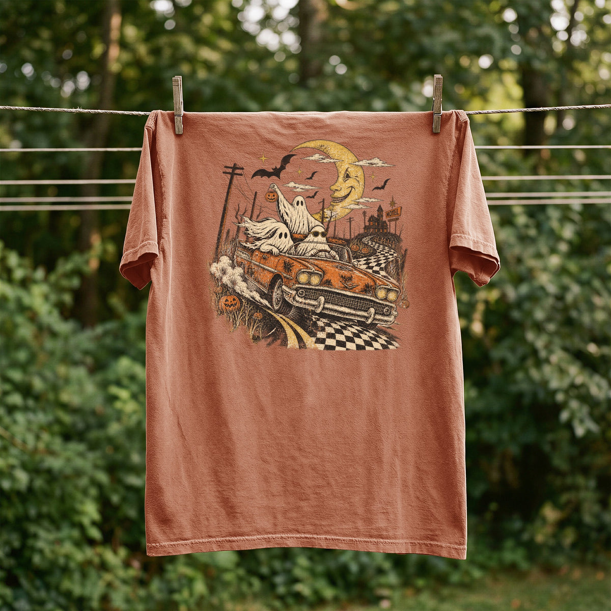 T-shirt with Halloween ghosts driving a convertible, spooky moon, and motel sign.