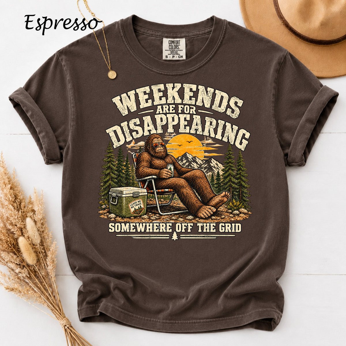 Bigfoot relaxing in a chair with a cooler and mountains, text reads "Weekends are for disappearing somewhere off the grid."