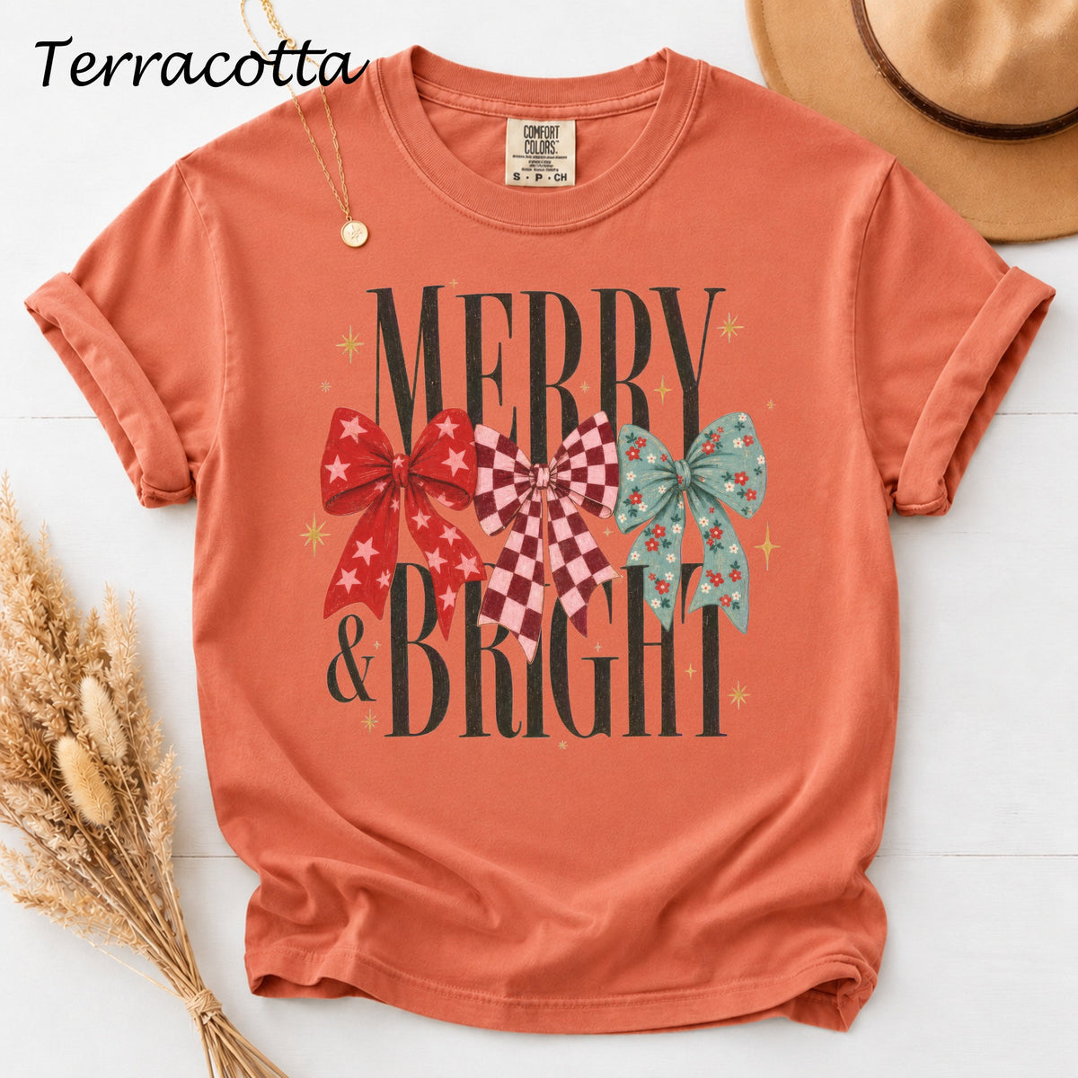 Terracotta t-shirt with "Merry & Bright" text and three decorative bows.