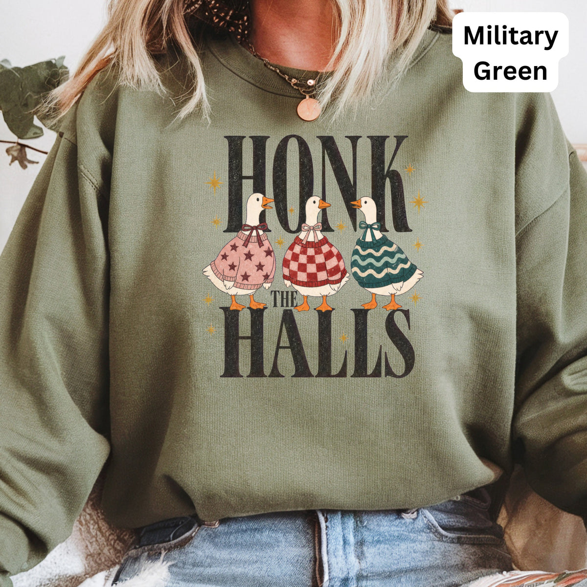 Three ducks wear festive sweaters, above text "HONK THE HALLS" on a military green sweatshirt.