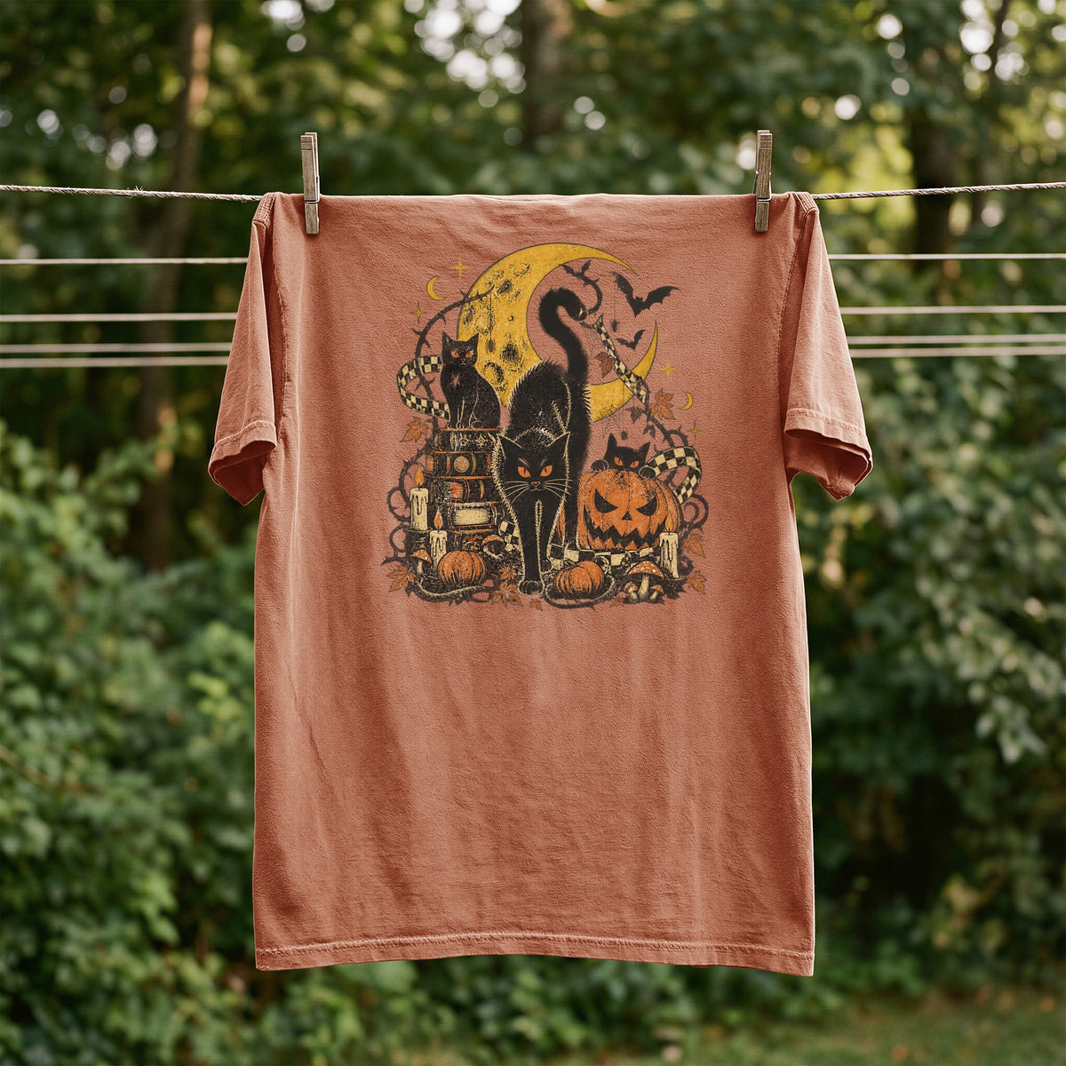 T-shirt with black cats, moon, pumpkins, bats, and checkered elements graphic.