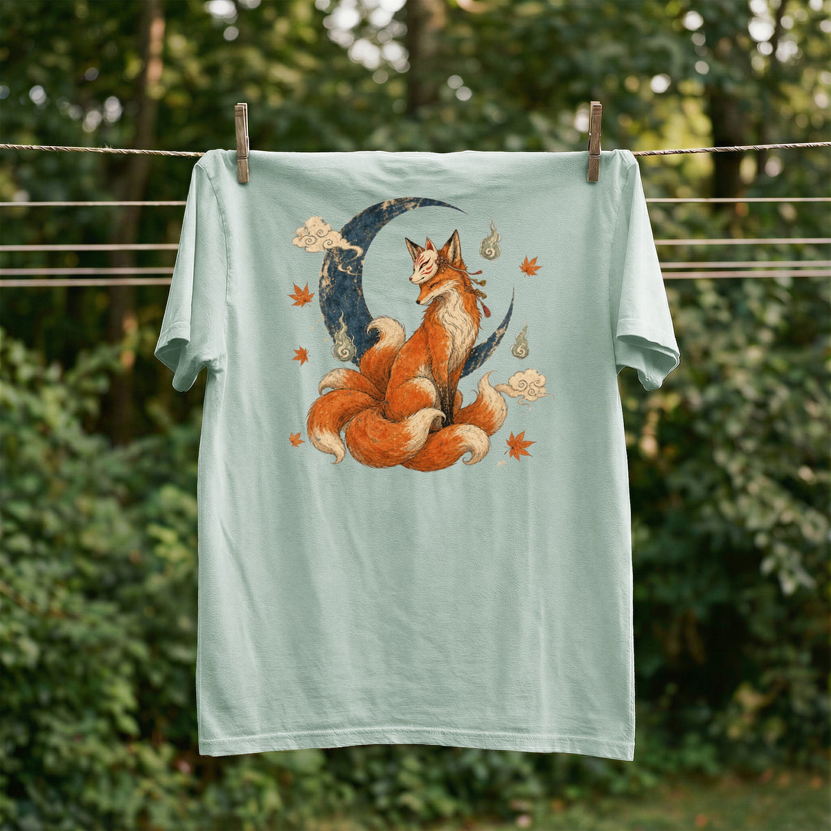 Mint t-shirt featuring a nine-tailed fox sitting on a crescent moon with clouds and leaves.
