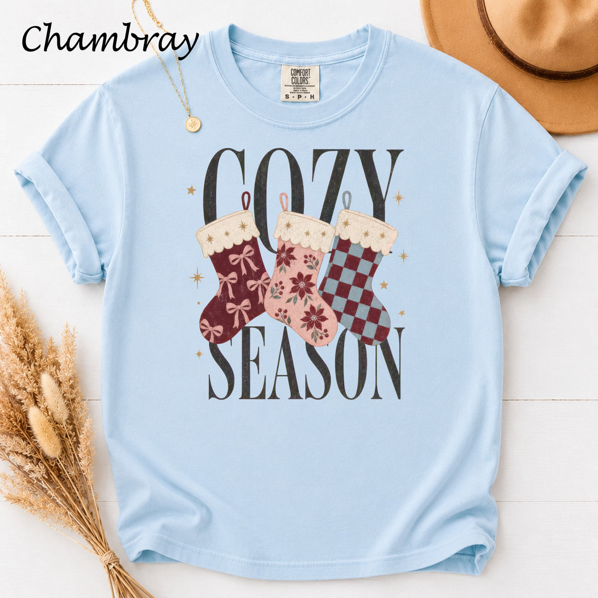 Light blue t-shirt with "Cozy Season" graphic featuring three decorative stockings.