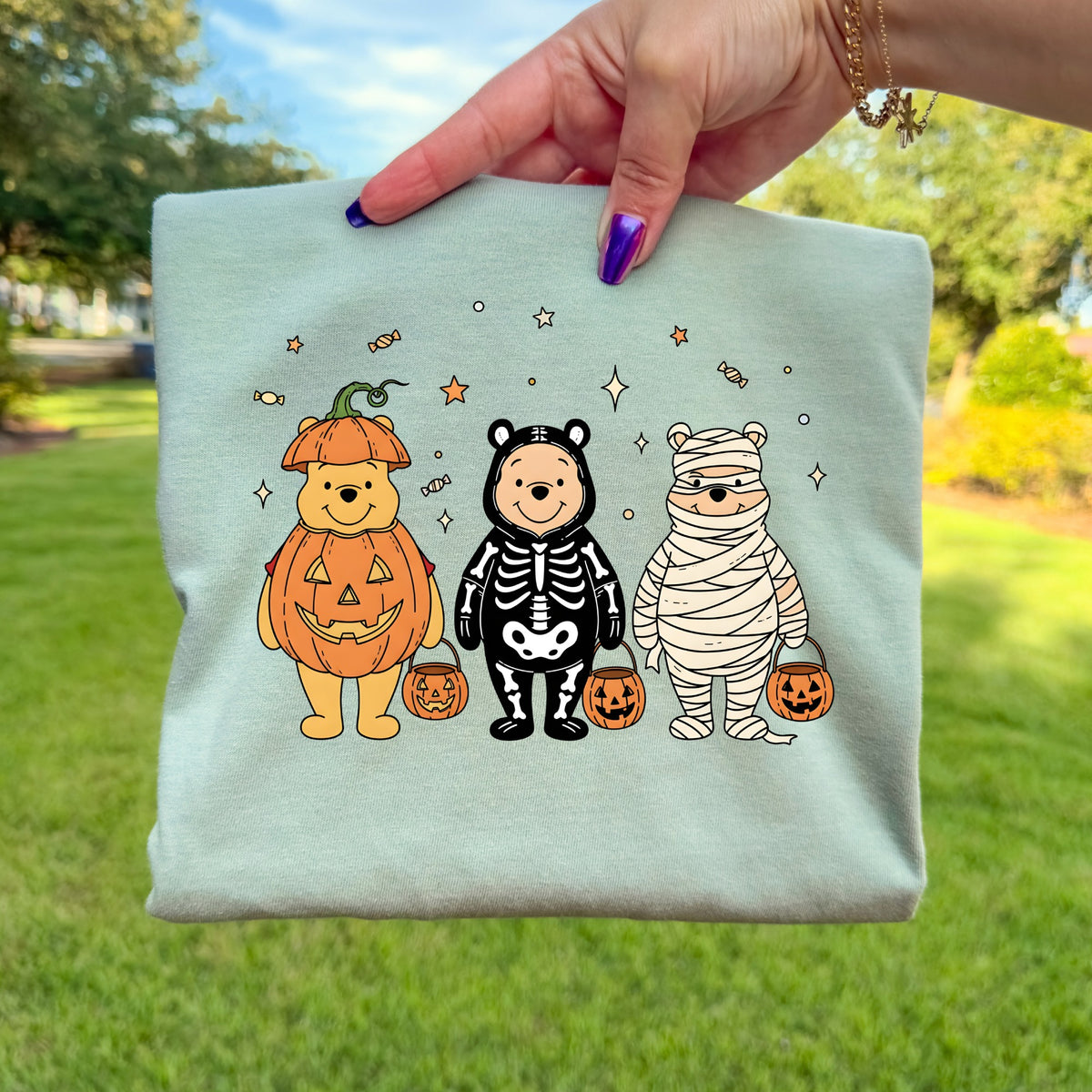 Three cartoon bears dressed as a pumpkin, skeleton, and mummy holding candy buckets.