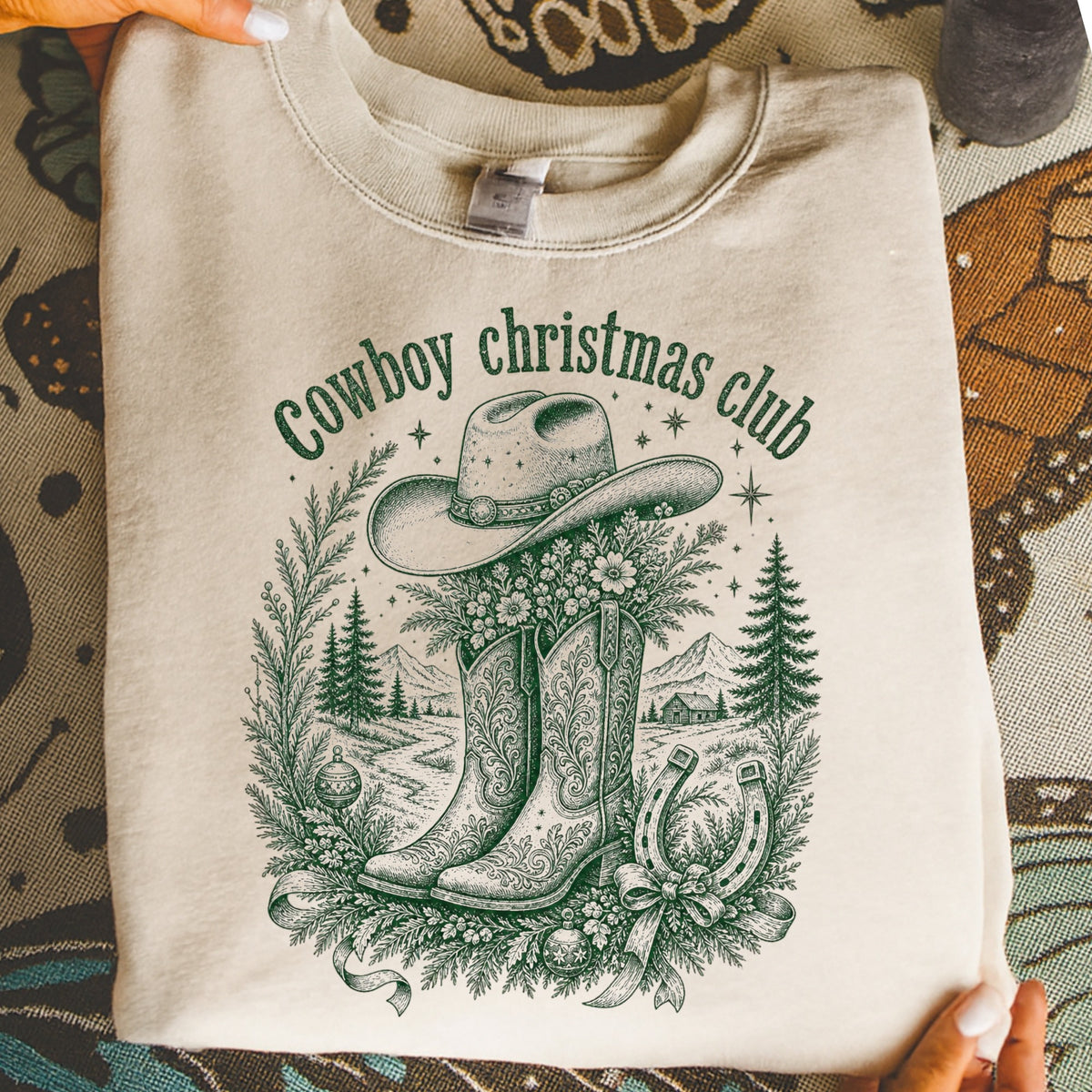 Light beige sweatshirt with a green graphic of cowboy boots, hat, horseshoe, and festive scene.
