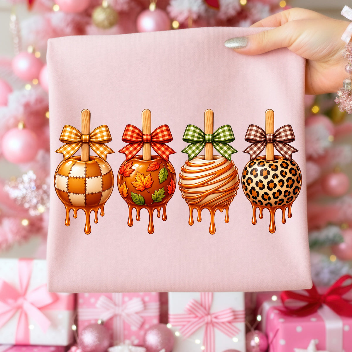 Four candy apples with decorative bows and drips on a pink fabric.