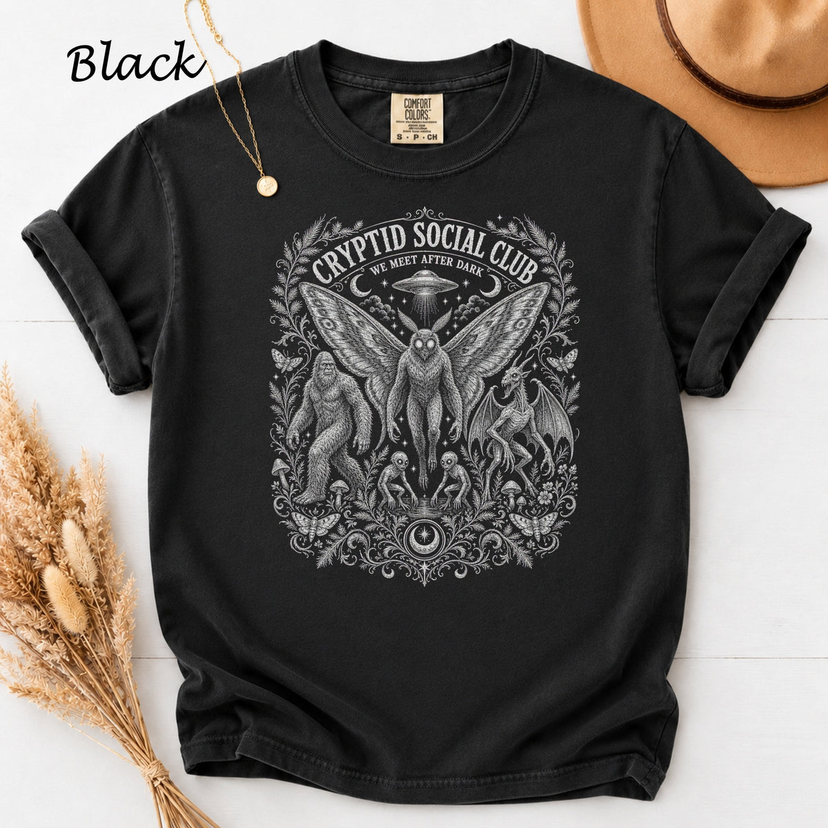 Black t-shirt with Cryptid Social Club graphic featuring Bigfoot, Mothman, and dragon.