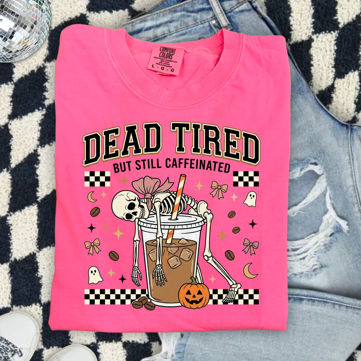 Pink t-shirt with skeleton drinking iced coffee and text "DEAD TIRED BUT STILL CAFFEINATED".